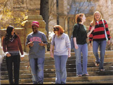 A diverse group of college students walks down some steps on a sunny day.