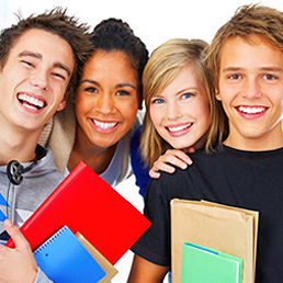 Four happy teenagers smile for a photo while holding books.