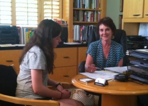 Lindy Kahn sits across from a student at a desk in an office.